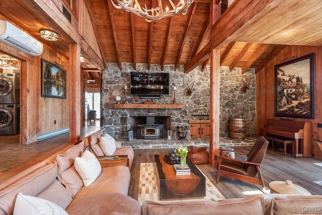 living room with a wood stove, an AC wall unit, wood walls, stacked washer / dryer, and baseboard heating