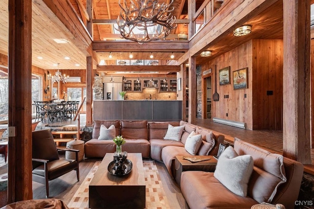 living area featuring wood walls, a high ceiling, an inviting chandelier, and wood finished floors