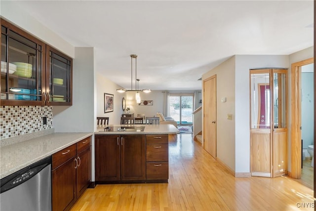 kitchen featuring light wood-style flooring, tasteful backsplash, stainless steel dishwasher, a peninsula, and black electric stovetop