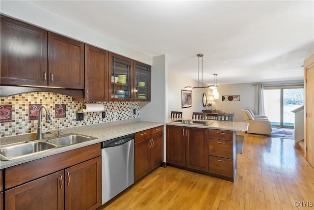 kitchen with stainless steel dishwasher, a peninsula, light countertops, and light wood-type flooring