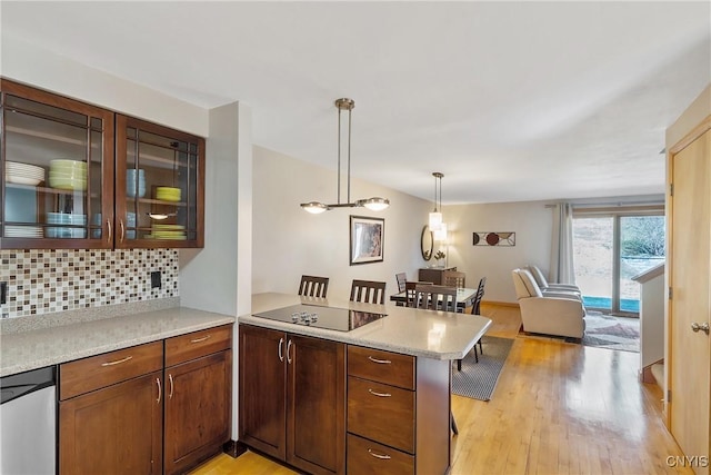 kitchen with tasteful backsplash, light wood-style floors, a peninsula, glass insert cabinets, and black electric stovetop