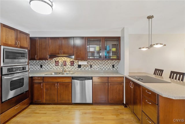 kitchen featuring a sink, tasteful backsplash, stainless steel appliances, a peninsula, and light countertops