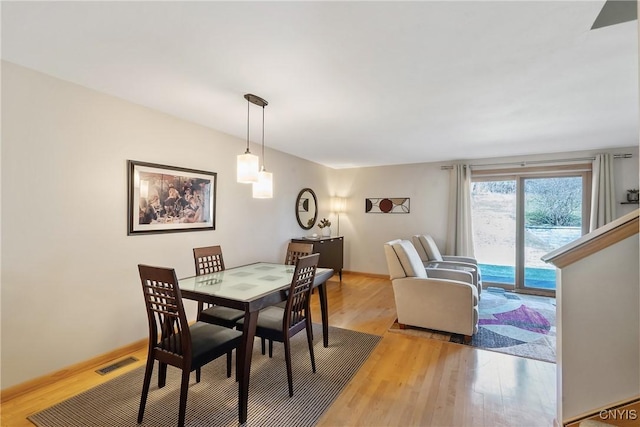 dining space featuring visible vents, light wood-style flooring, and baseboards