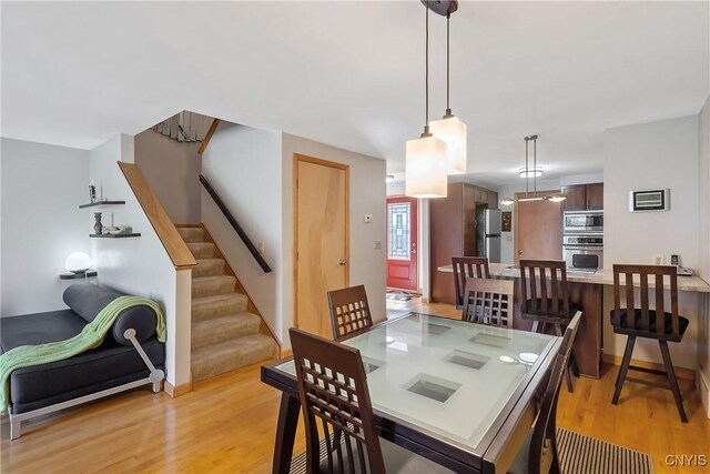 dining area with light wood-type flooring and stairway