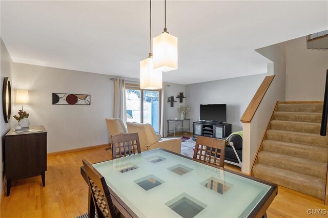 dining room with stairway, light wood-type flooring, and baseboards