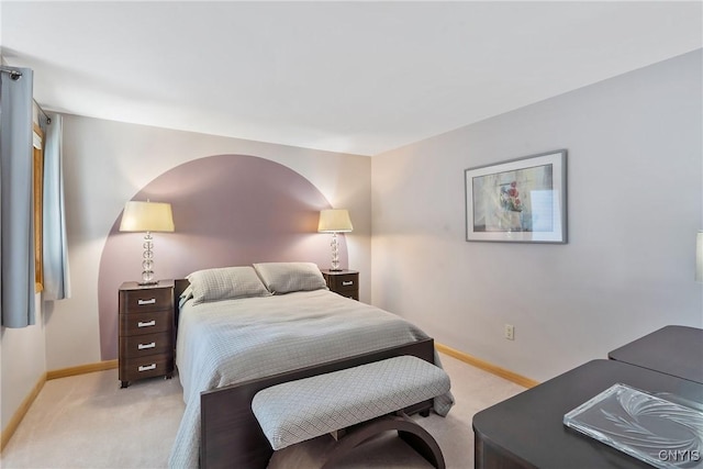 bedroom with light colored carpet and baseboards