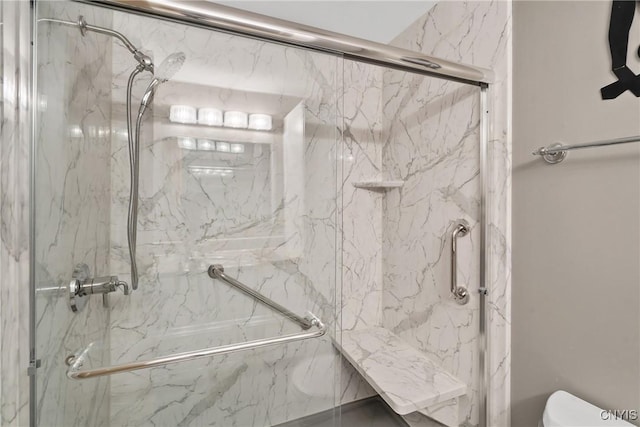 bathroom featuring a marble finish shower and toilet