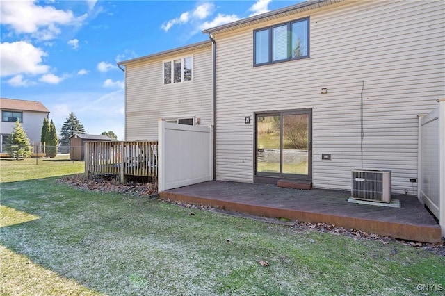 rear view of property featuring a lawn, cooling unit, a wooden deck, and fence