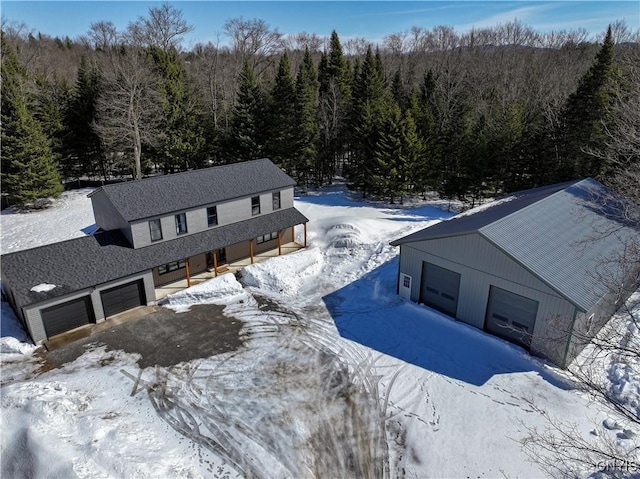 snowy aerial view featuring a forest view