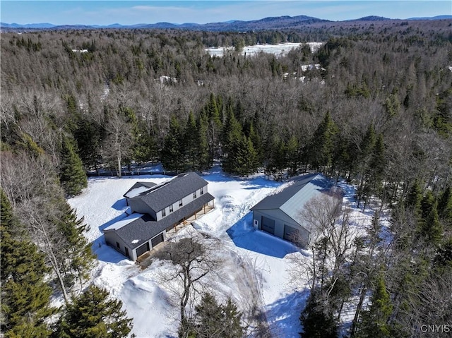 snowy aerial view with a mountain view and a wooded view