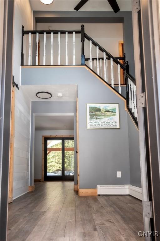 entryway with a towering ceiling, stairs, baseboards, and wood finished floors