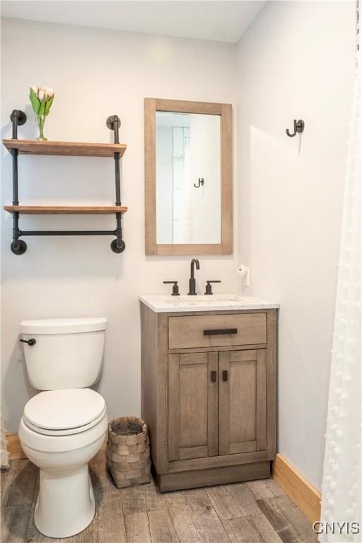 bathroom featuring vanity, toilet, baseboards, and wood tiled floor