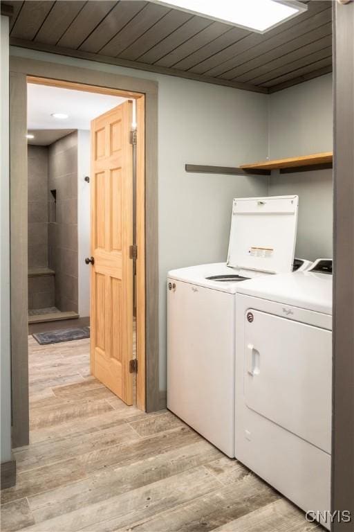 laundry room with laundry area, wood ceiling, light wood-type flooring, and separate washer and dryer