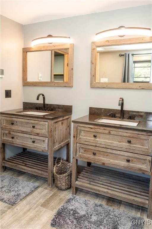 bathroom with wood finished floors, two vanities, and a sink