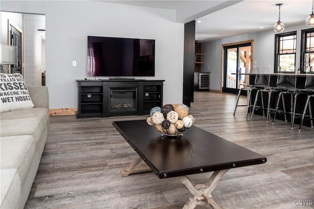 living area with recessed lighting, a glass covered fireplace, and wood finished floors