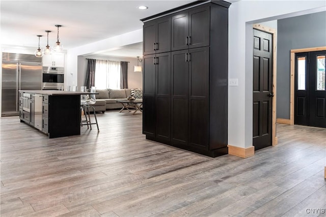 living area with recessed lighting, light wood-style floors, and baseboards