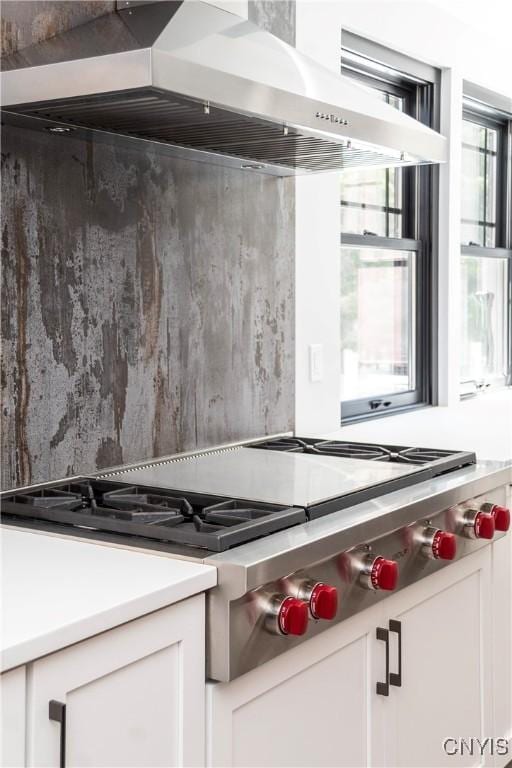 kitchen with extractor fan, white cabinets, light countertops, and stainless steel gas cooktop