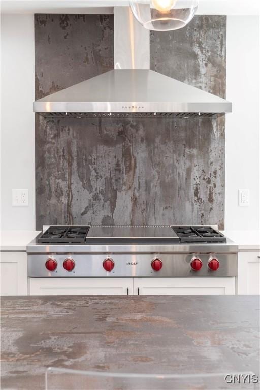 room details with white cabinetry, light countertops, wall chimney range hood, and tasteful backsplash