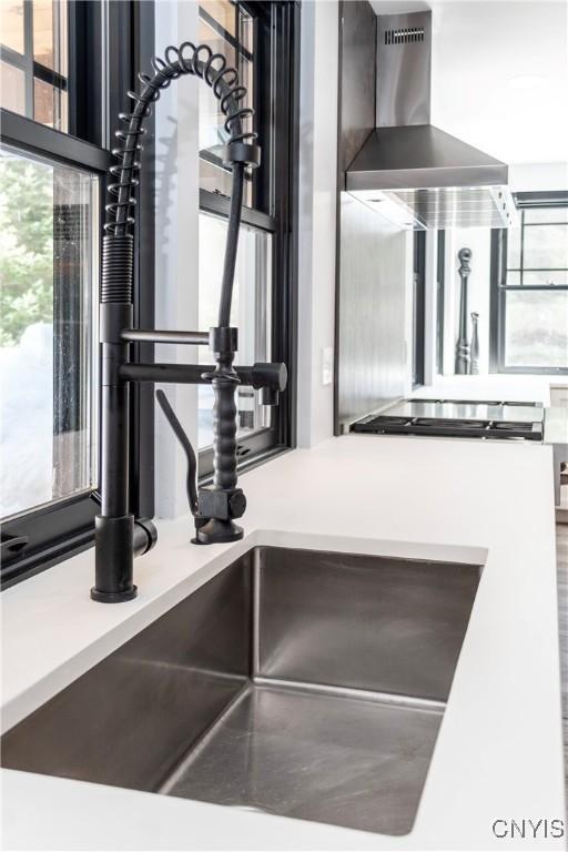 interior details featuring light countertops and wall chimney exhaust hood