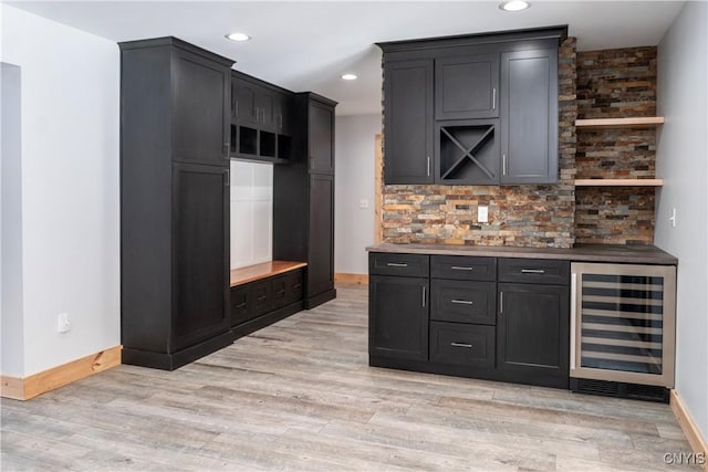 kitchen with decorative backsplash, wine cooler, light wood-style flooring, and baseboards