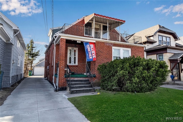 view of front of property featuring an outbuilding, a detached garage, a front yard, a balcony, and brick siding