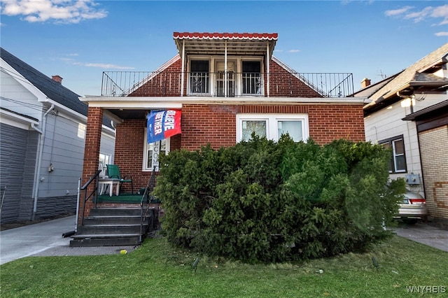 view of front facade featuring brick siding and a balcony