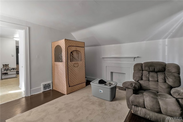 sitting room featuring visible vents, wood finished floors, and vaulted ceiling