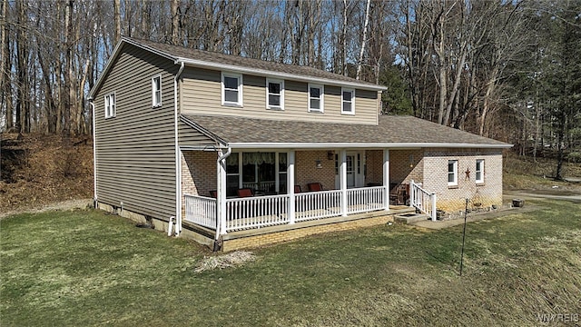 view of front of property featuring brick siding, a porch, a shingled roof, and a front yard