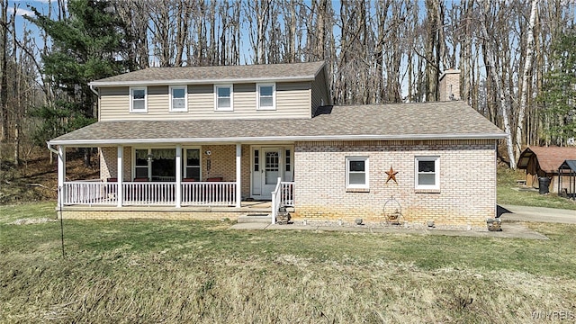 view of front of home with brick siding, a porch, a front yard, and roof with shingles