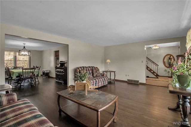 living room featuring visible vents, baseboards, stairs, wood finished floors, and a notable chandelier