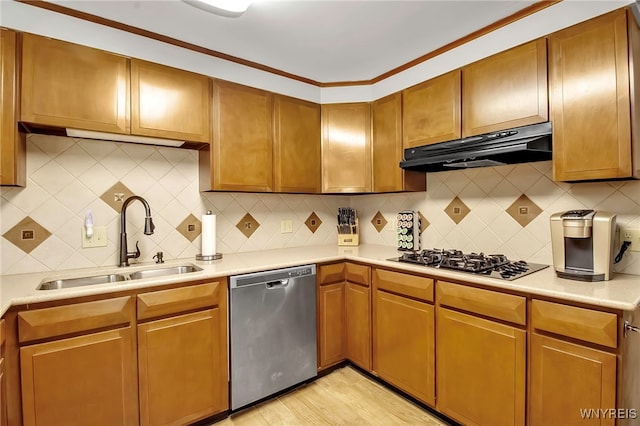 kitchen with under cabinet range hood, a sink, tasteful backsplash, appliances with stainless steel finishes, and light countertops