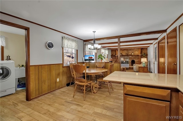 dining space with crown molding, wainscoting, light wood-style flooring, a notable chandelier, and washer / clothes dryer