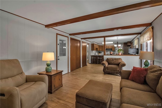 living room with beam ceiling, a notable chandelier, and light wood-type flooring