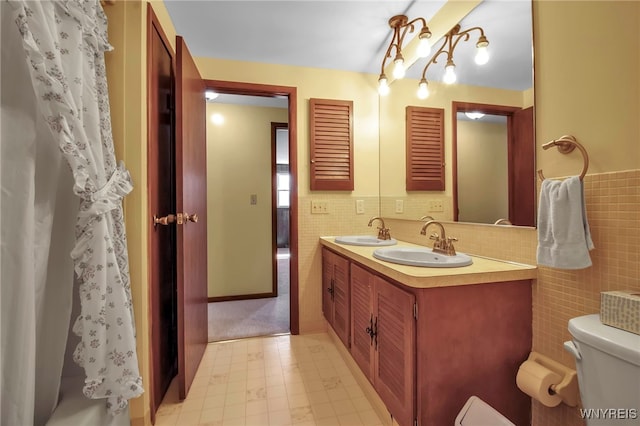 full bath featuring toilet, tile walls, and a sink