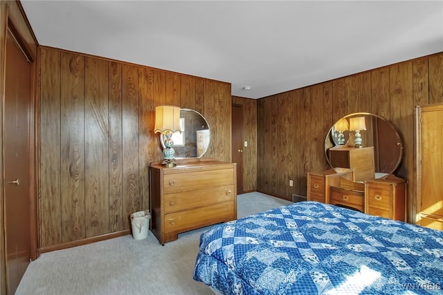 bedroom with light carpet, wood walls, and baseboards