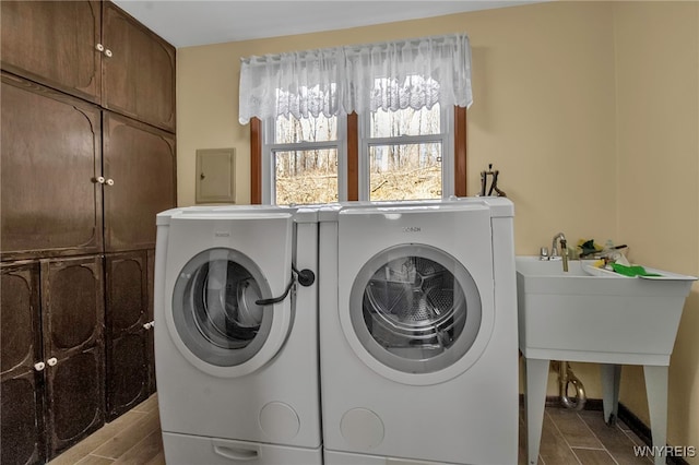 laundry room featuring a sink, cabinet space, separate washer and dryer, and electric panel