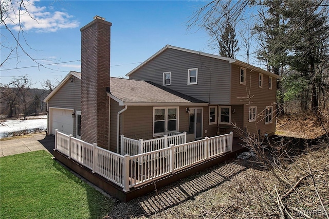 rear view of property with concrete driveway, a lawn, a chimney, a deck, and a garage