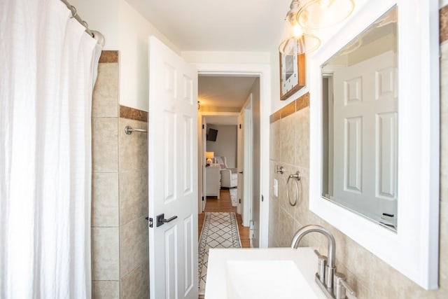 full bath featuring a sink, tile walls, and a tile shower