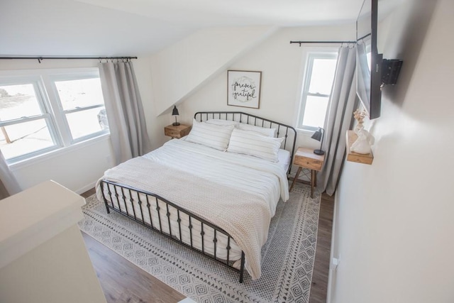 bedroom featuring lofted ceiling, wood finished floors, and baseboards