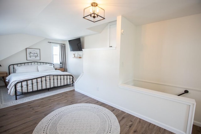 bedroom featuring a chandelier, baseboards, wood finished floors, and vaulted ceiling