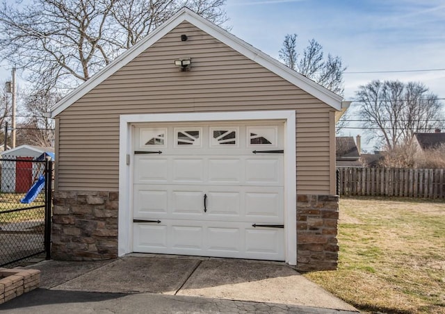 detached garage with concrete driveway and fence