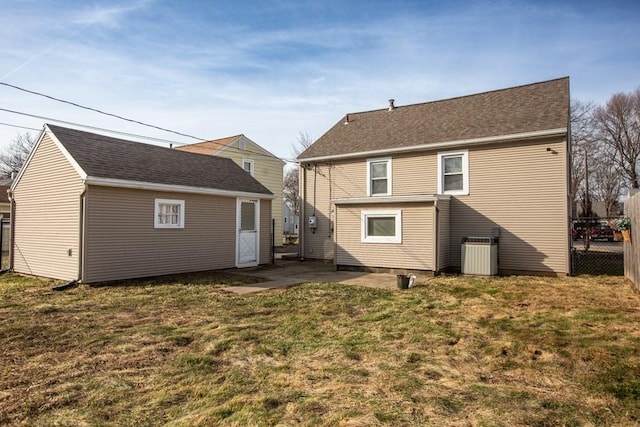 rear view of house featuring fence, central air condition unit, a yard, an outbuilding, and a patio