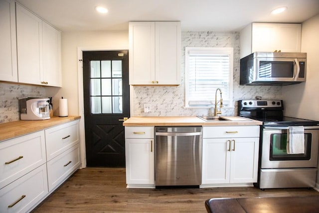 kitchen featuring dark wood-type flooring, butcher block countertops, appliances with stainless steel finishes, and a sink