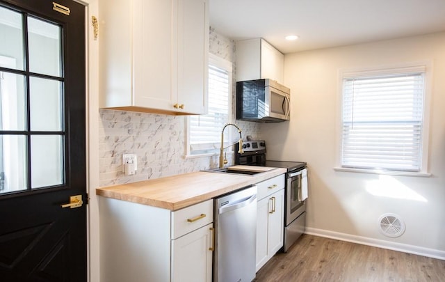 kitchen featuring visible vents, decorative backsplash, white cabinets, stainless steel appliances, and wood counters