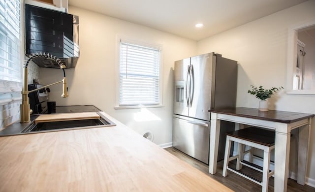 kitchen with recessed lighting, baseboards, stainless steel refrigerator with ice dispenser, and wood finished floors