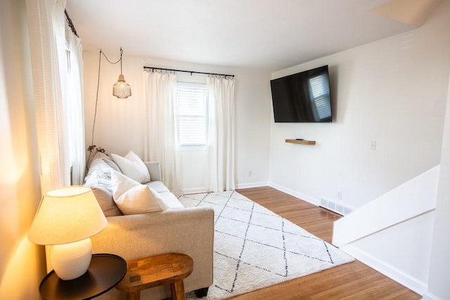 living area with visible vents, baseboards, and wood finished floors