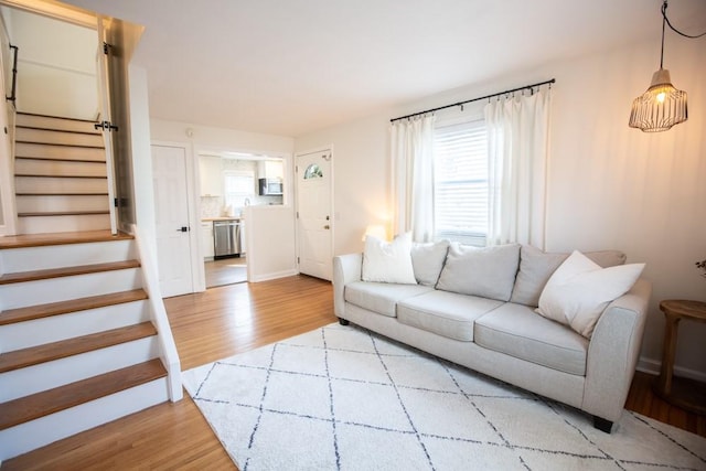 living room featuring stairs and light wood-style floors