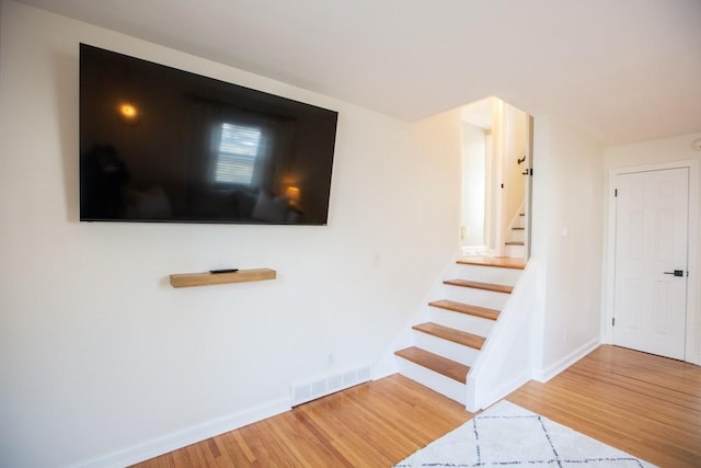 stairway featuring visible vents, baseboards, and wood finished floors