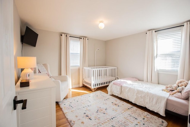 bedroom with light wood finished floors and multiple windows