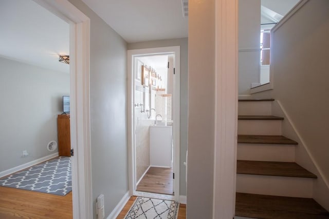 stairs with visible vents, wood finished floors, and baseboards